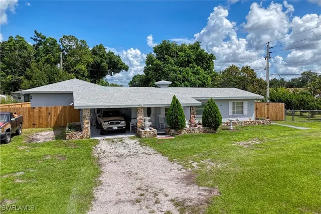 a front view of a house with a garden and trees