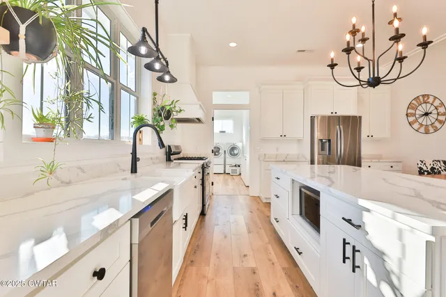 a large white kitchen with a large stove a sink dishwasher and a stove with wooden floor