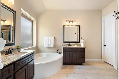 a spacious bathroom with a tub sink and mirror