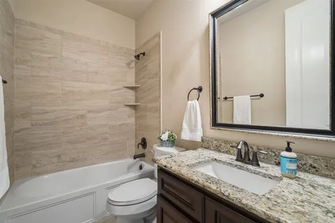 a bathroom with a granite countertop toilet a sink and a bathtub
