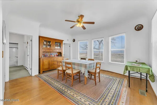 a dining room with wooden floor a chandelier fan a wooden table and chairs
