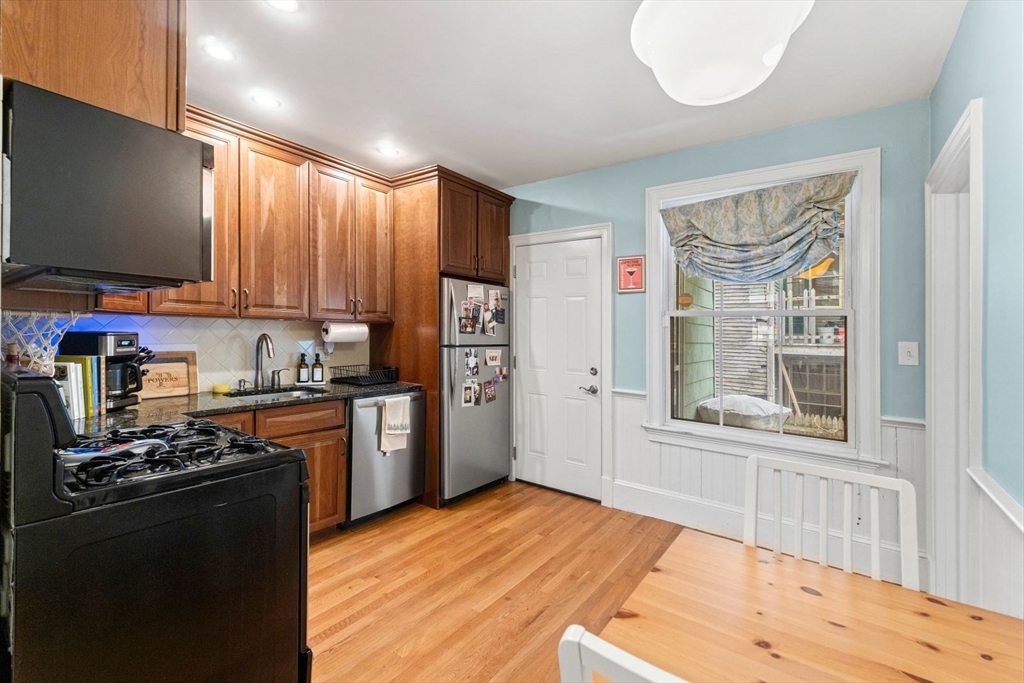 51-53 Story Street, Unit 1 Boston, MA 02127 - Photo 10 of 33 a kitchen with stainless steel appliances granite countertop a stove top oven a sink dishwasher and a refrigerator with wooden floor