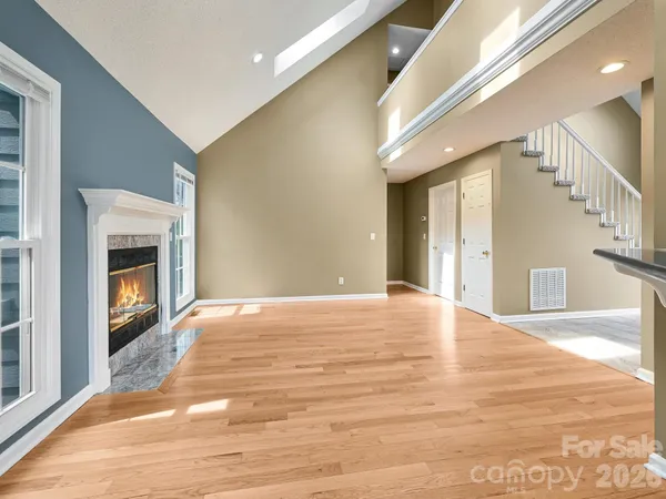 a view of an empty room with wooden floor fireplace and a window