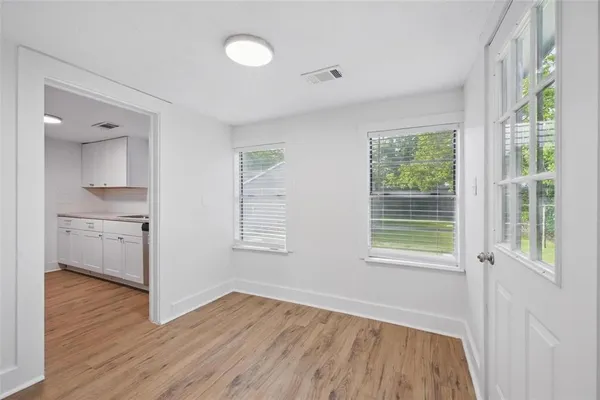 a view of an empty room with wooden floor and a window