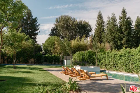 a view of a patio with table and chairs potted plants and large tree