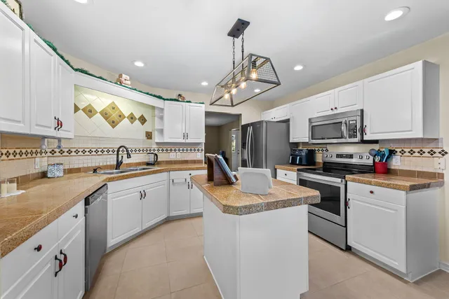 a kitchen with stainless steel appliances granite countertop a sink dishwasher stove top oven and refrigerator