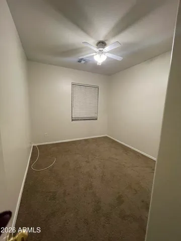 an empty room with a ceiling fan and carpet