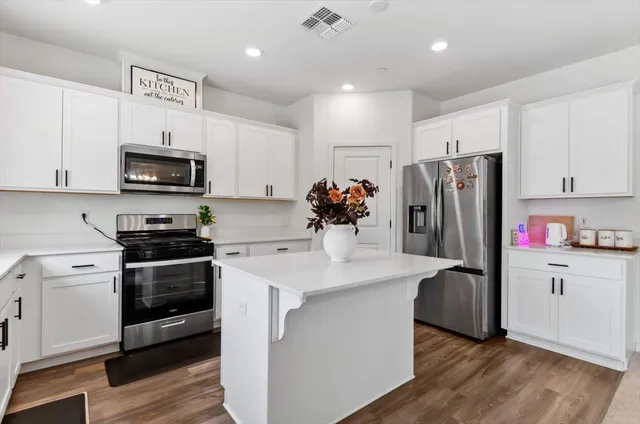 a kitchen with stainless steel appliances white cabinets and a stove top oven