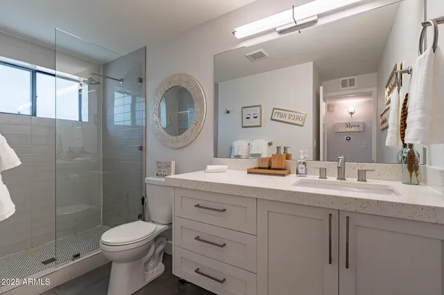 a bathroom with a double vanity sink toilet mirror and shower