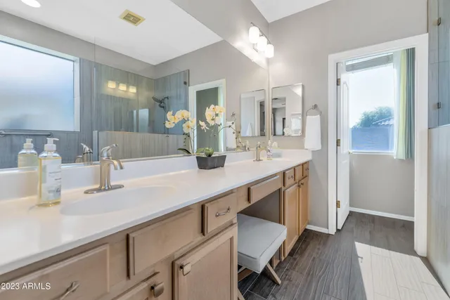 a bathroom with a sink double vanity granite tub shower and a mirror