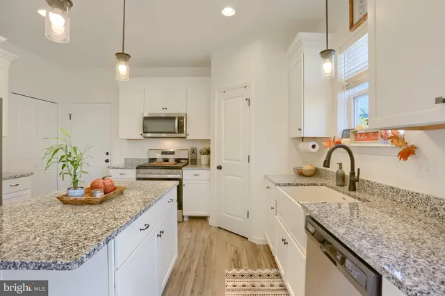 a dining room with stainless steel appliances kitchen island granite countertop a dining table chairs and white cabinets