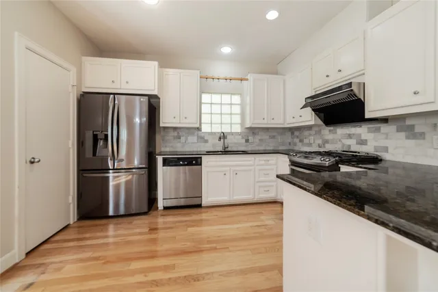 a kitchen with a sink a stove a refrigerator and white cabinets