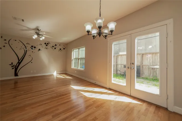 a view of an empty room with a window and wooden floor