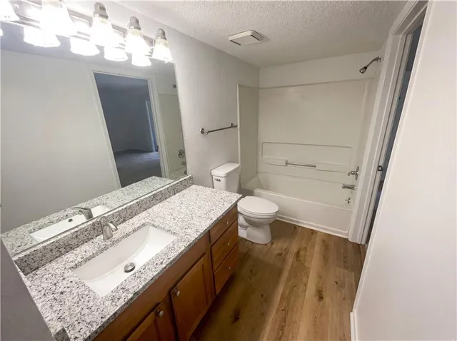 a bathroom with a granite countertop sink a toilet and bathtub