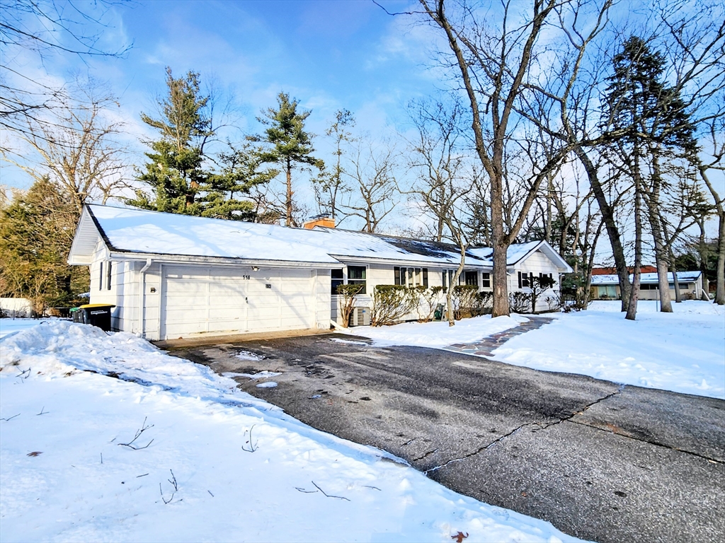a front view of a house with a yard covered with snow and trees