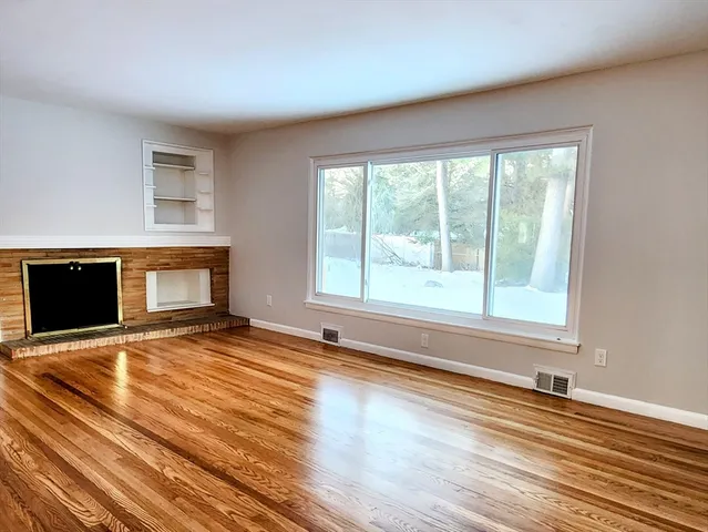 a view of empty room with wooden floor and fireplace