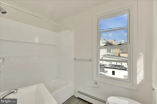 a bathroom with a window a toilet and a shower