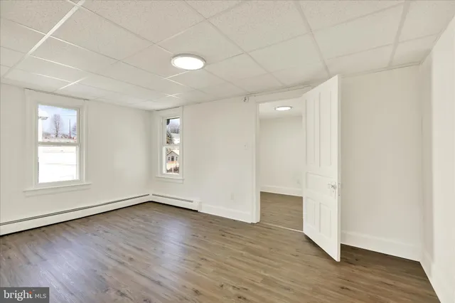 an empty room with wooden floor and windows