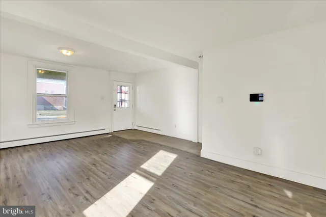 an empty room with wooden floor and window