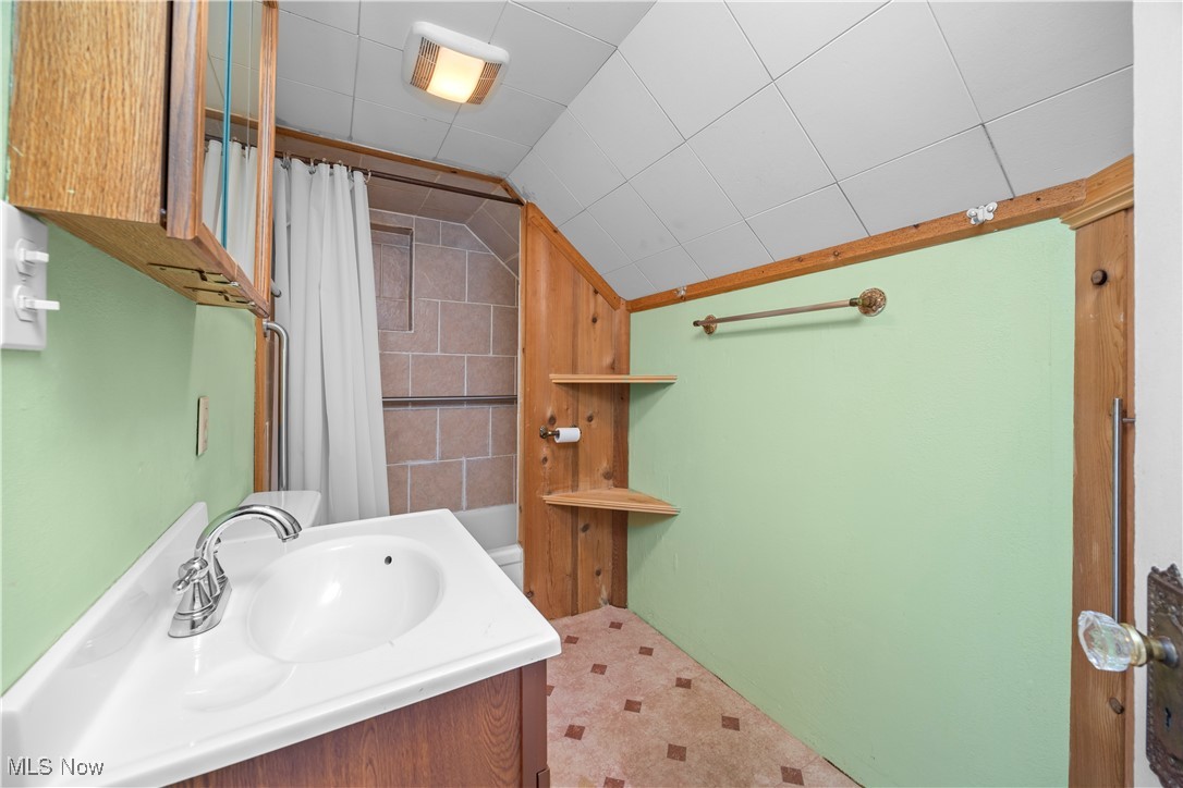 6927 North Wildacre Road Curtice, OH 43412 - Photo 24 of 44 Bathroom with vanity, shower / tub combo with curtain, lofted ceiling, and light flooring