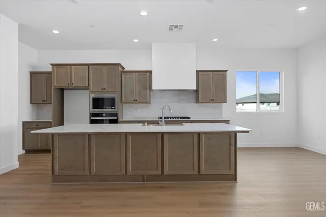 a kitchen with kitchen island a sink stainless steel appliances and cabinets