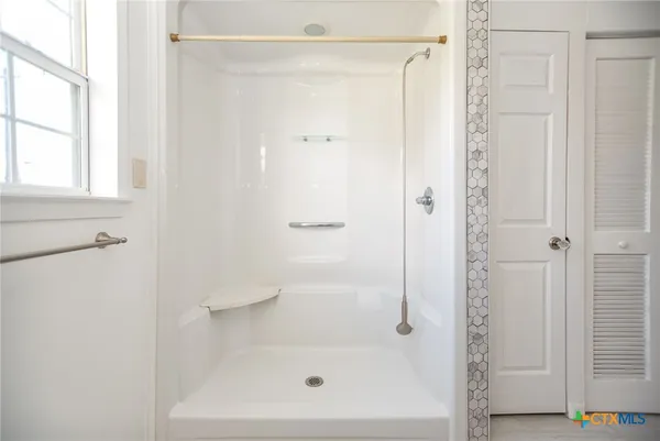 an empty room with wooden floor chandelier fan and windows