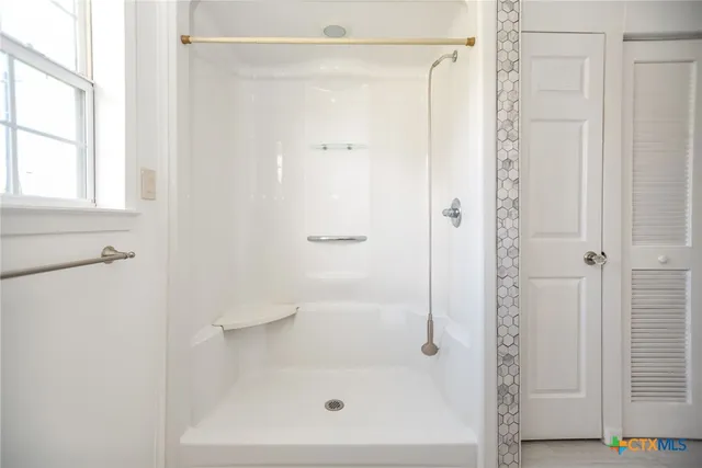 an empty room with wooden floor chandelier fan and windows