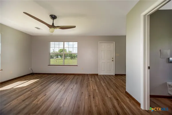 a view of an empty room with wooden floor and a window
