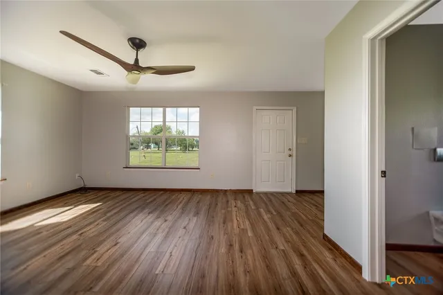 a view of an empty room with wooden floor and a window