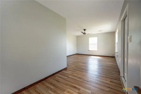 a view of an empty room with wooden floor and a window