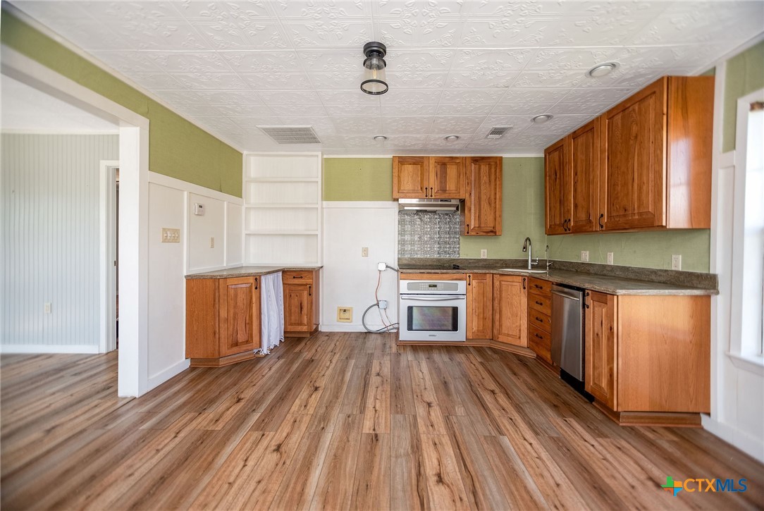 512 McDowell Street Austwell, TX 77950 - Photo 5 of 30 a kitchen with granite countertop wooden floors a refrigerator and a sink