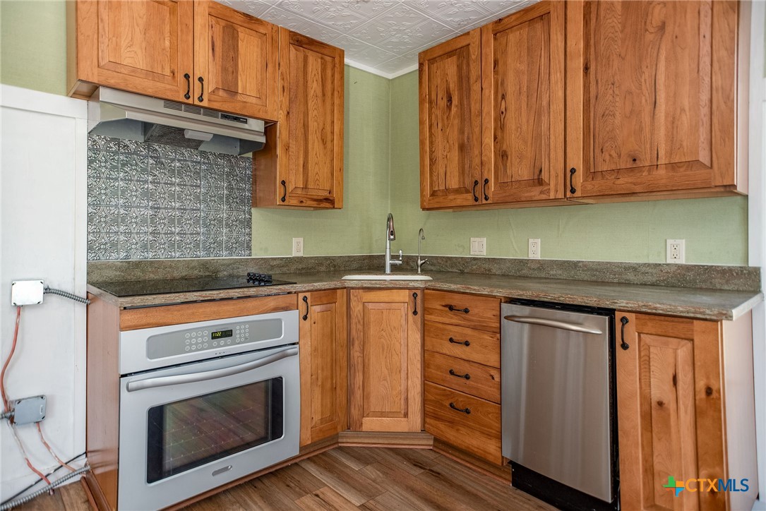 512 McDowell Street Austwell, TX 77950 - Photo 8 of 30 a kitchen with stainless steel appliances granite countertop wooden cabinets a sink and dishwasher