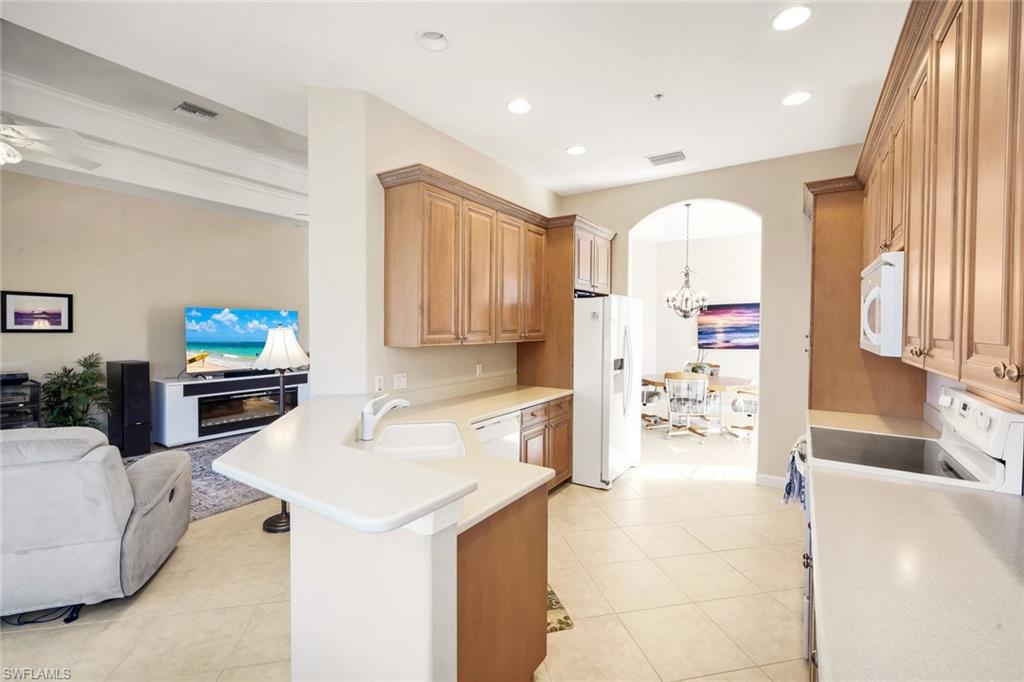 8771 Coastline Court, Unit 201 Naples, FL 34120 - Photo 15 of 49 a kitchen with stainless steel appliances kitchen island granite countertop a sink and a refrigerator