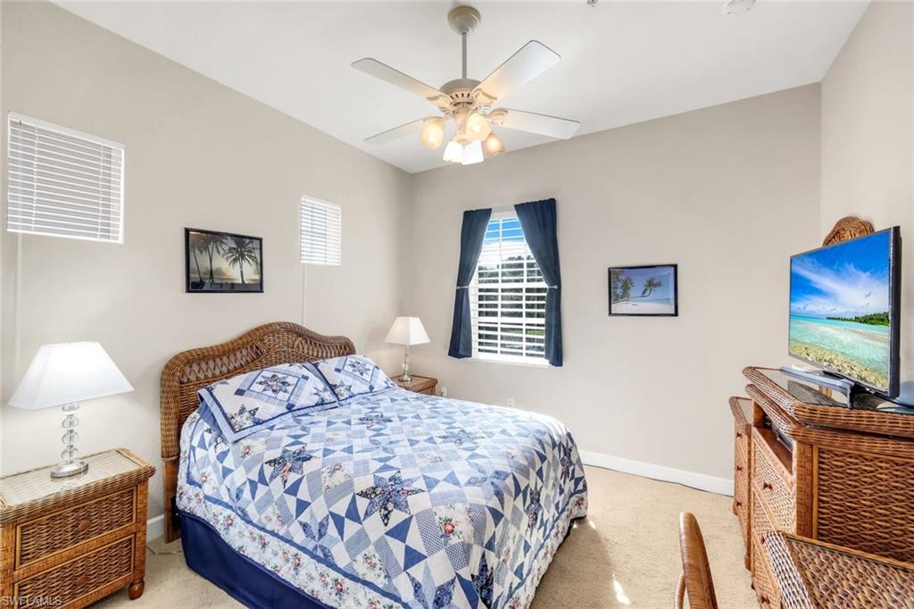 8771 Coastline Court, Unit 201 Naples, FL 34120 - Photo 26 of 49 a bedroom with a bed and a chandelier