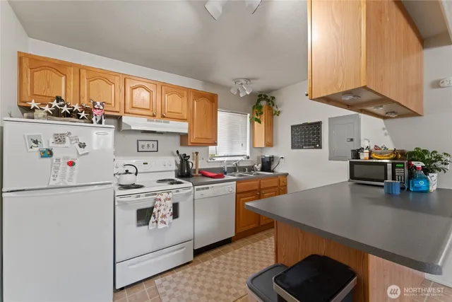 a kitchen with stainless steel appliances granite countertop a stove a sink dishwasher and a refrigerator with wooden cabinets