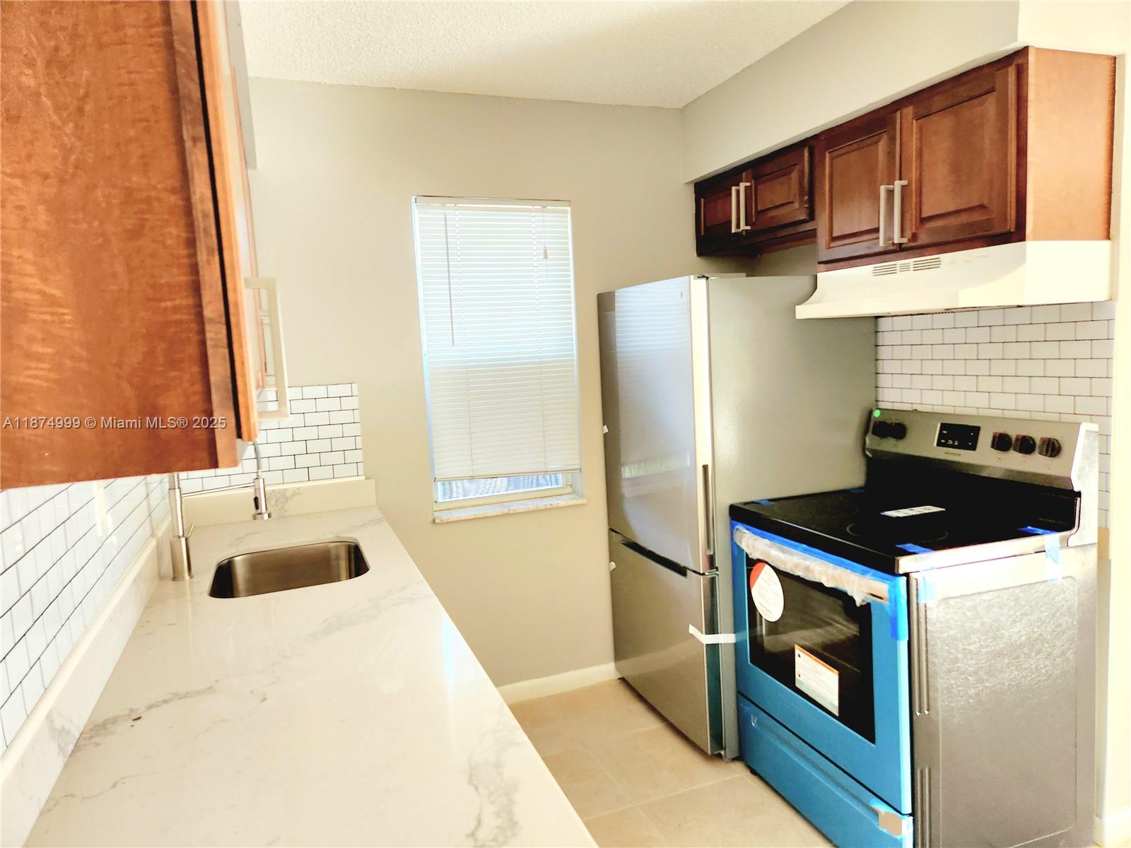 191 Southwest 15th Street, Unit 201 Pompano Beach, FL 33060 - Photo 3 of 10 a kitchen with stainless steel appliances kitchen island a stove and a refrigerator