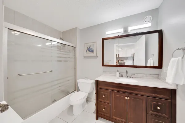 a bathroom with a toilet a sink a mirror a shower a vanity and window