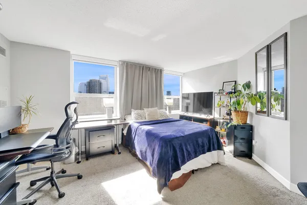 a bedroom with a bed table chair and a window
