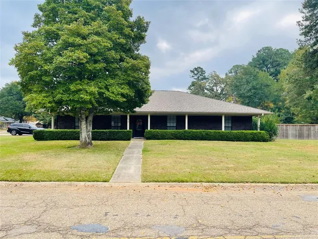 a front view of a house with a garden and trees