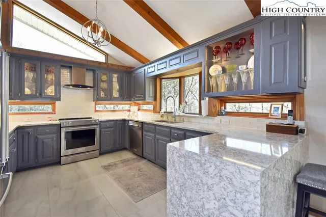 a large kitchen with stainless steel appliances granite countertop a stove and large window