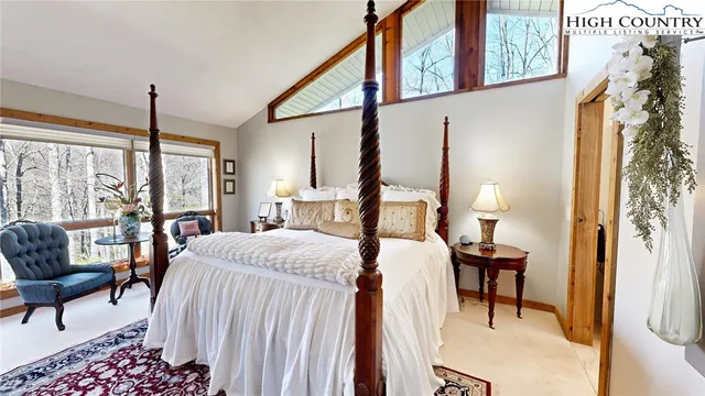 a bedroom with a bed a lamp and a large window with outer view