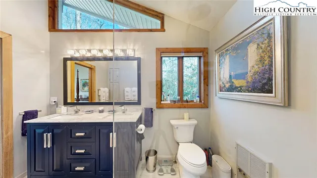 a bathroom with a toilet a sink a mirror and a window