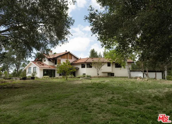 a white house with a big yard and large trees
