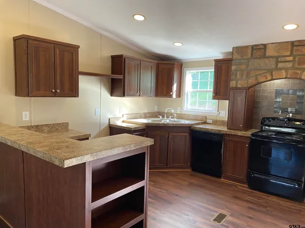 a kitchen with kitchen island granite countertop a sink cabinets and stainless steel appliances