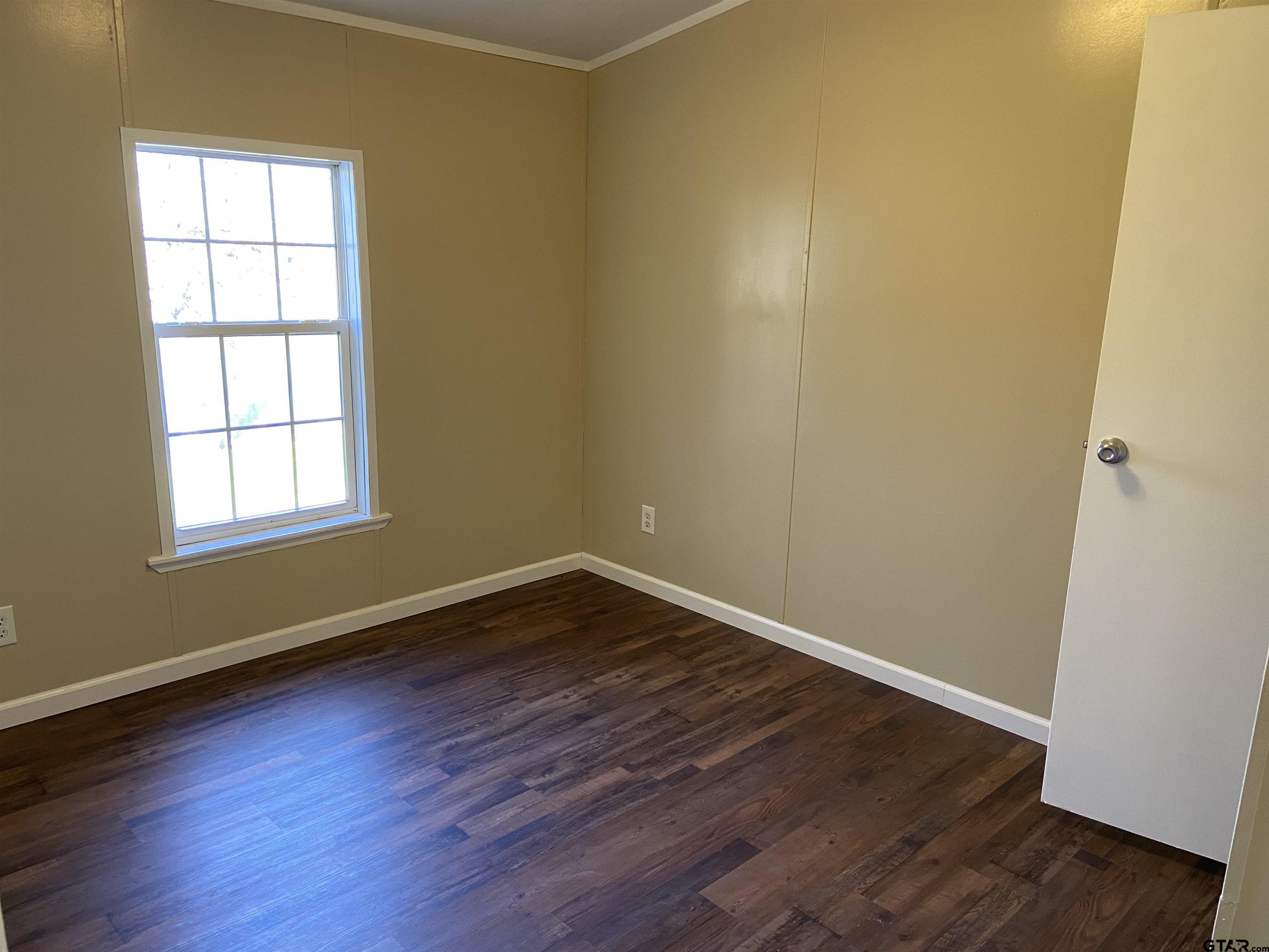 58 Florey Lake Road Kilgore, TX 75662 - Photo 10 of 14 an empty room with wooden floor and windows