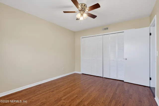 a view of a room with wooden floor and a ceiling fan