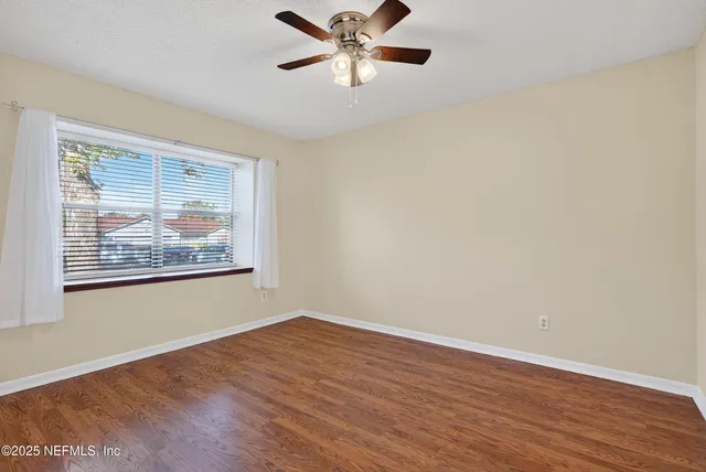 a view of an empty room with window and wooden floor