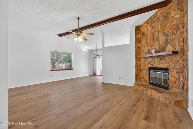 a view of an empty room with window and wooden floor