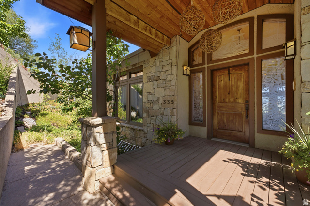 335 Bern Way Midway, UT 84049 - Photo 77 of 88 Stone exterior entryway featuring a solid wood door, sidelight windows, overhead woven light fixtures, and a wood-finish porch