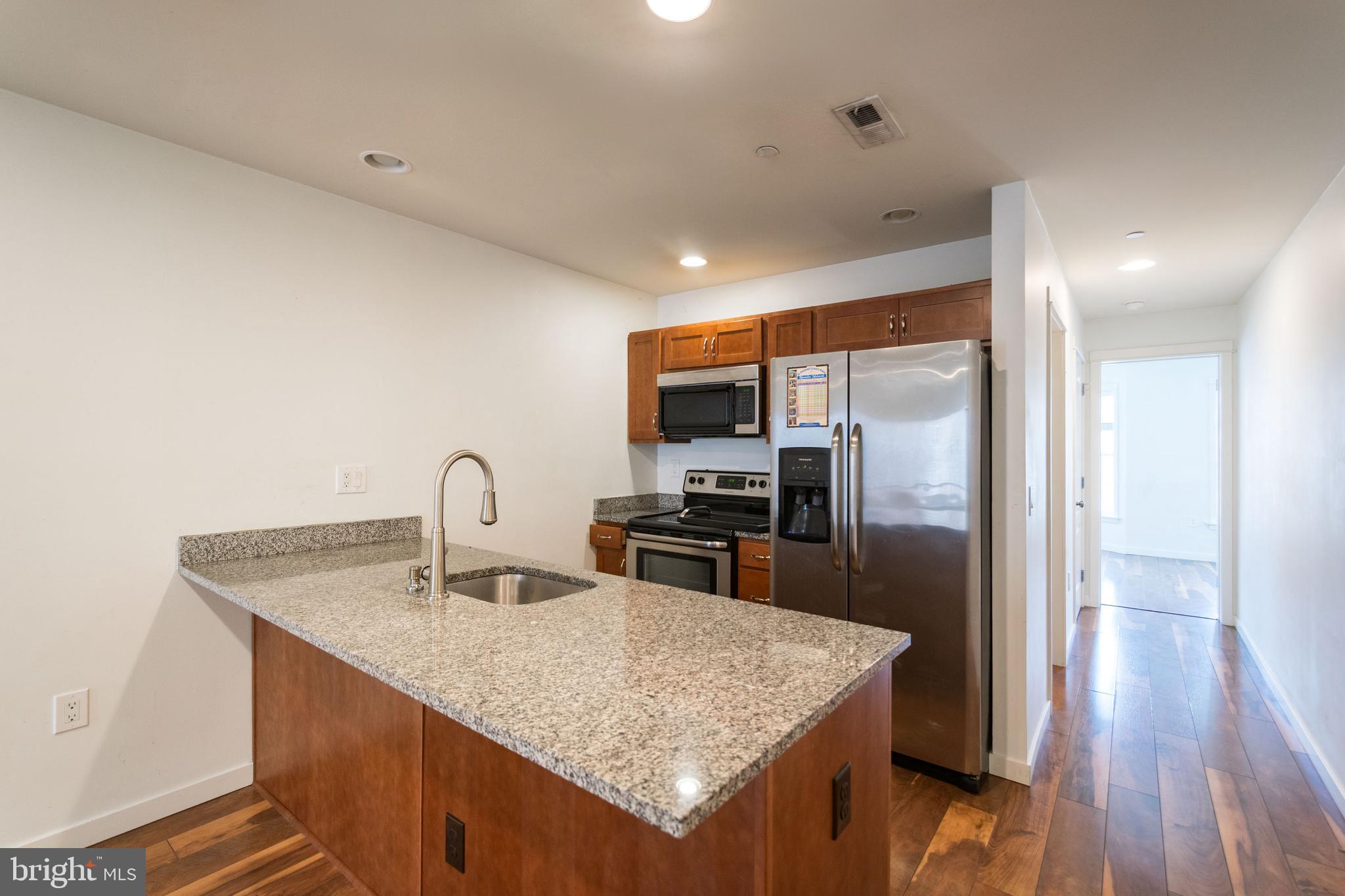 132 South 46th Street, Unit B Philadelphia, PA 19139 - Photo 2 of 15 a kitchen with granite countertop kitchen island a sink appliances and cabinets